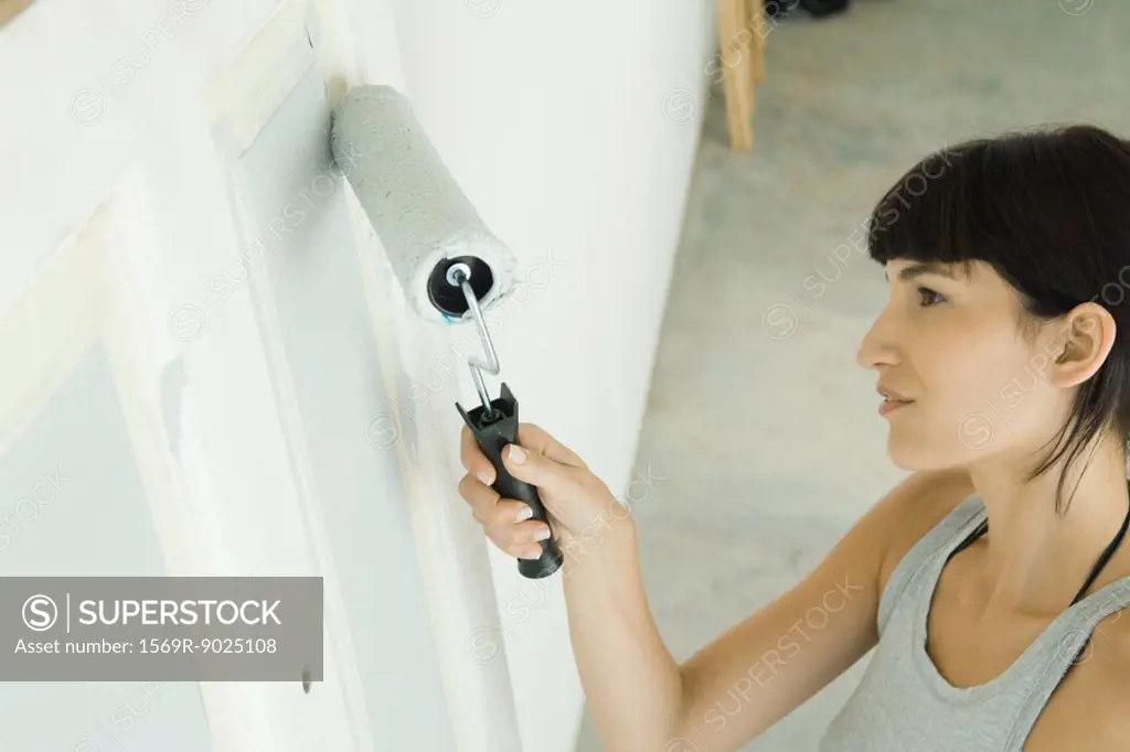 Woman painting door with paint roller