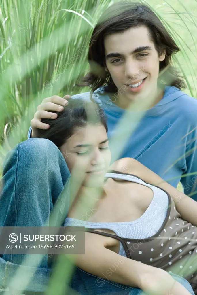 Young couple sitting in grass, woman leaning head against boyfriend´s knee