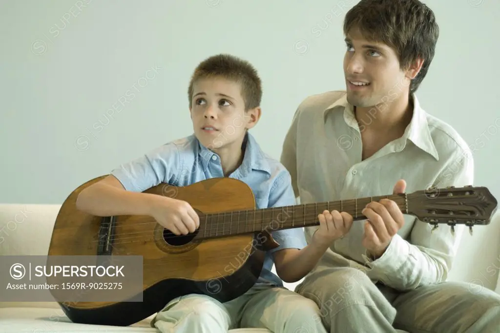 Man teaching boy to play the guitar