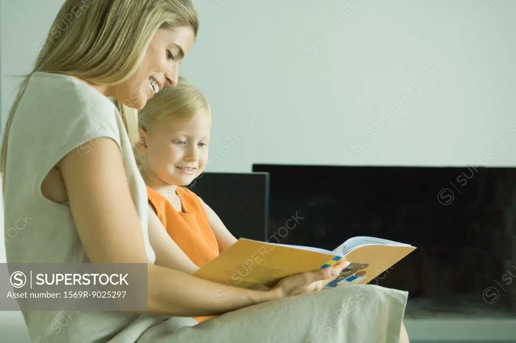 Woman reading book with little girl