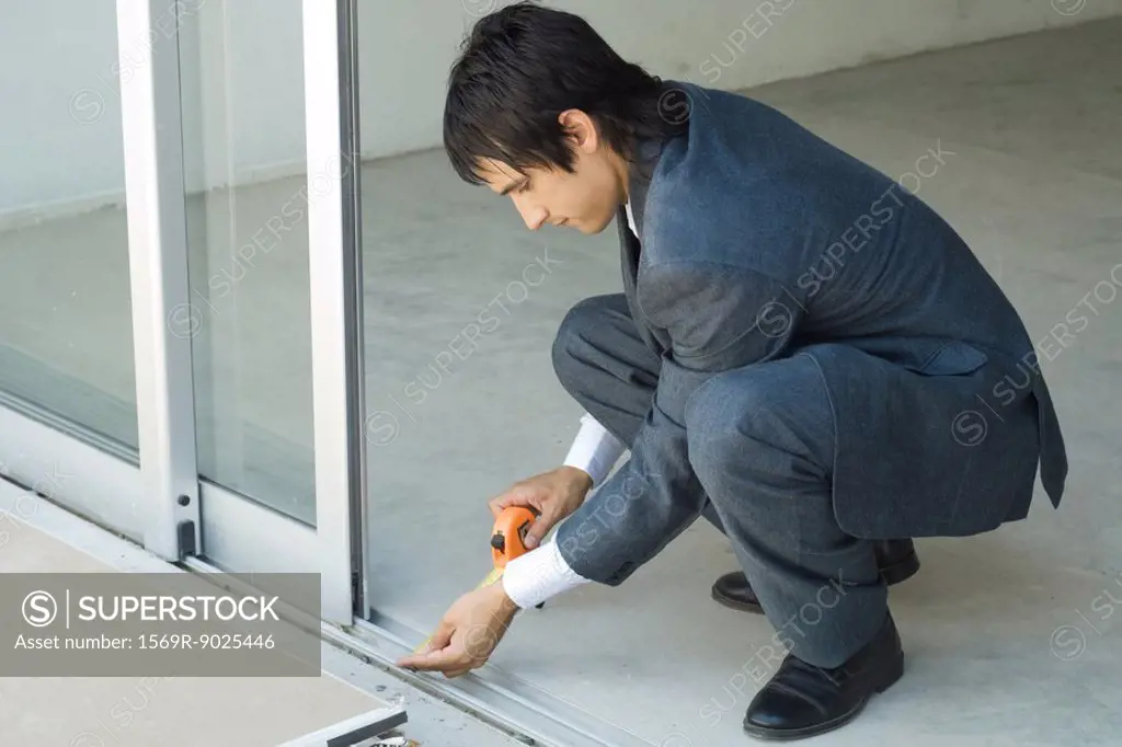 Man in suit taking measurements next to sliding glass door