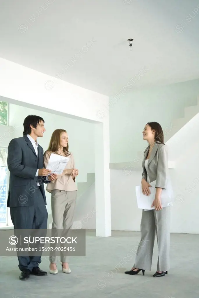 Female real estate agent showing house to young couple