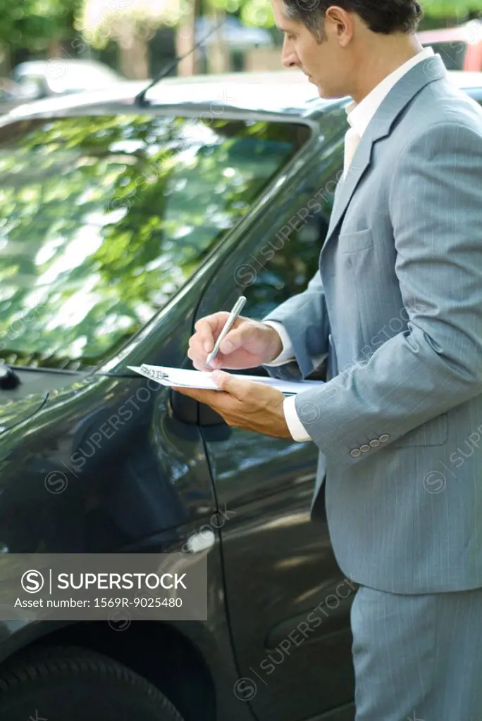 Mature man in suit inspecting car