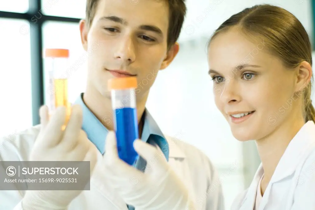 Young male and female scientists holding up test tubes
