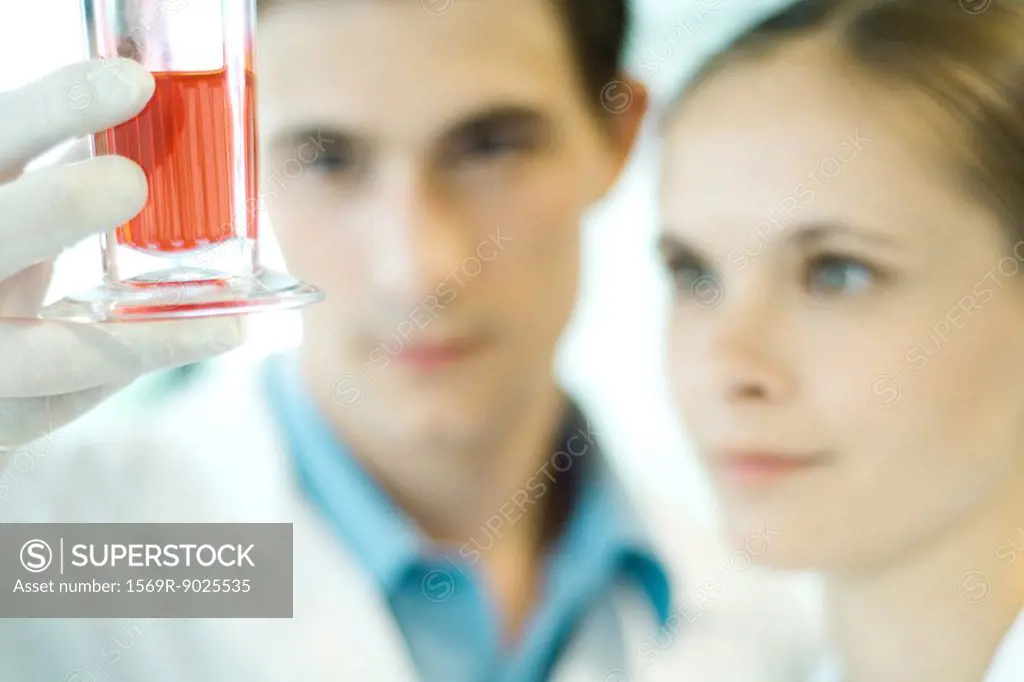 Young male and female scientists holding up beaker