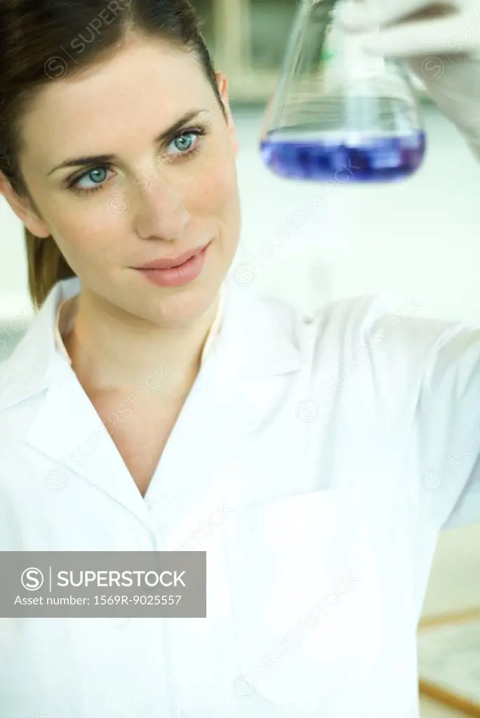 Female lab worker holding up flask