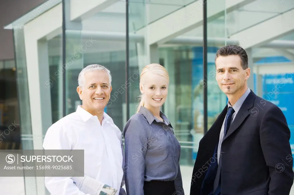 Three business associates smiling at camera, waist up, group portrait