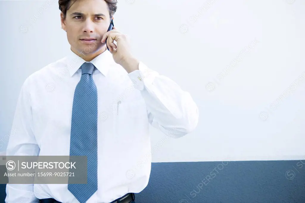 Young businessman using cell phone, looking away, close-up