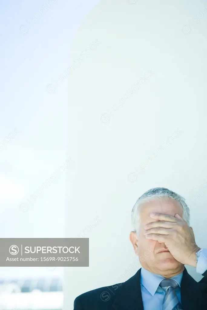 Mature businessman, hand covering eyes, head and shoulders
