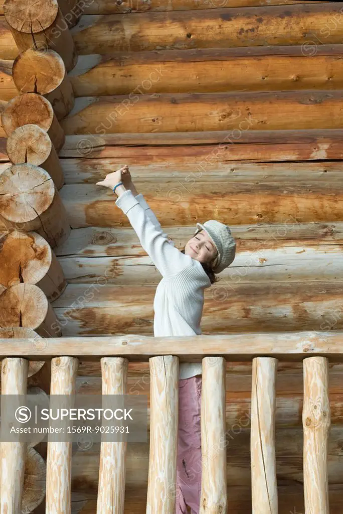 Girl standing on deck of wood cabin, stretching arms