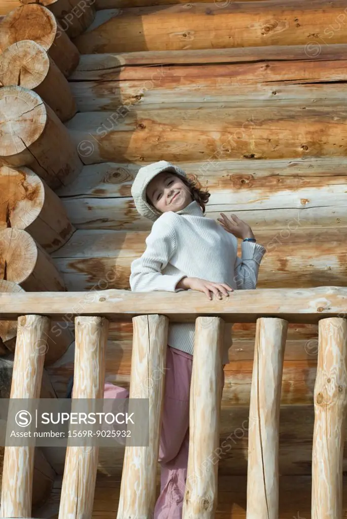 Girl standing on deck of wood cabin, striking a pose