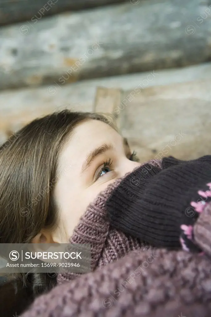 Teenage girl holding edge of sweater neck over face, looking up, close-up