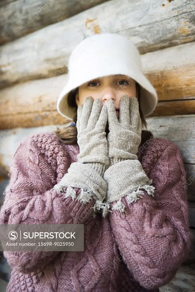 Teenage girl holding gloved hands over mouth