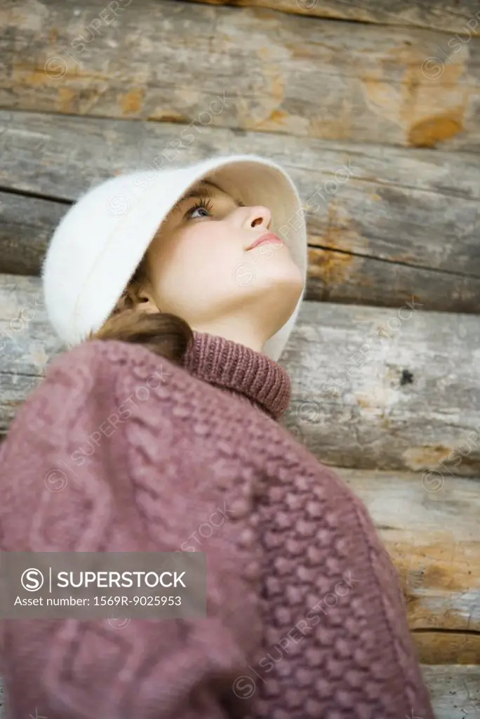 Teenage girl wearing hat and turtleneck, looking up, low angle view, portrait