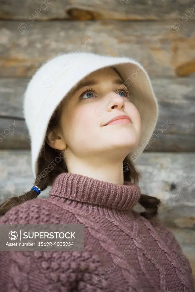 Teenage girl wearing hat and turtleneck, looking up, portrait