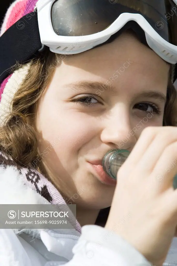 Girl wearing ski gear, drinking from bottle, close-up