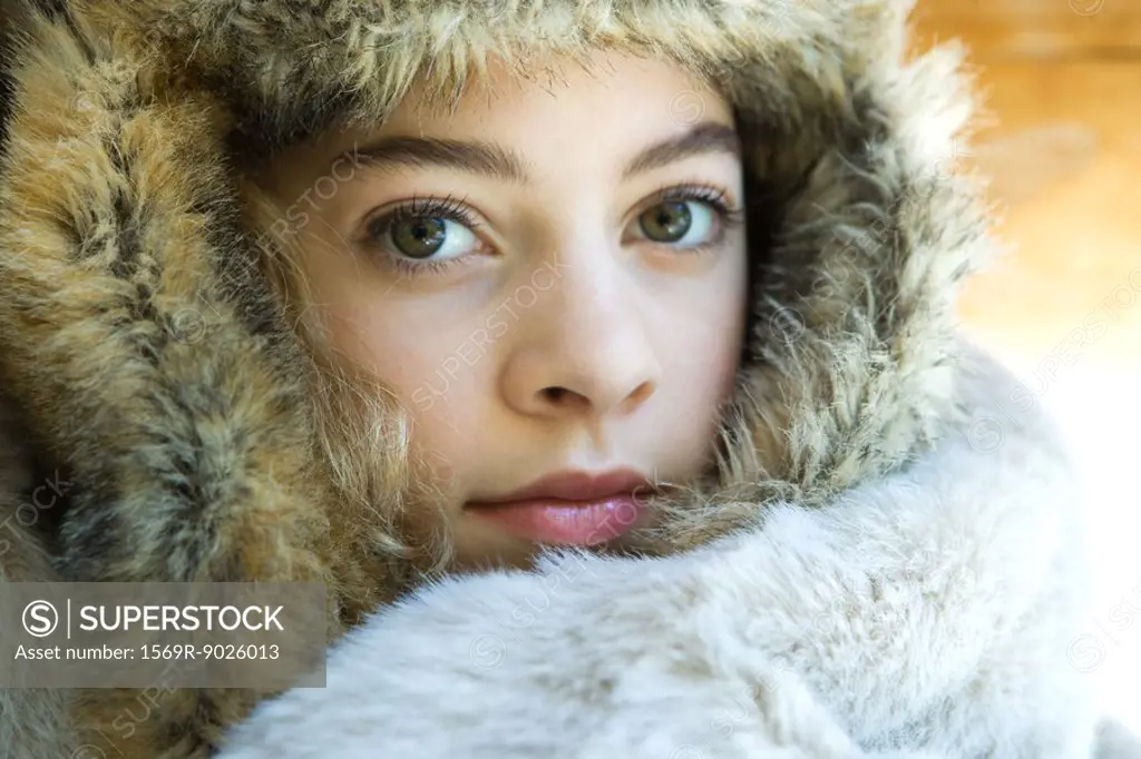 Preteen girl, wearing fur hat, wrapped in fur blanket, looking at camera, close-up portrait