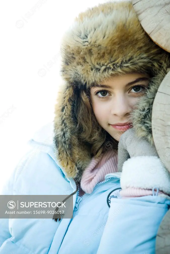 Preteen girl wearing fur hat and winter jacket, smiling at camera, portrait