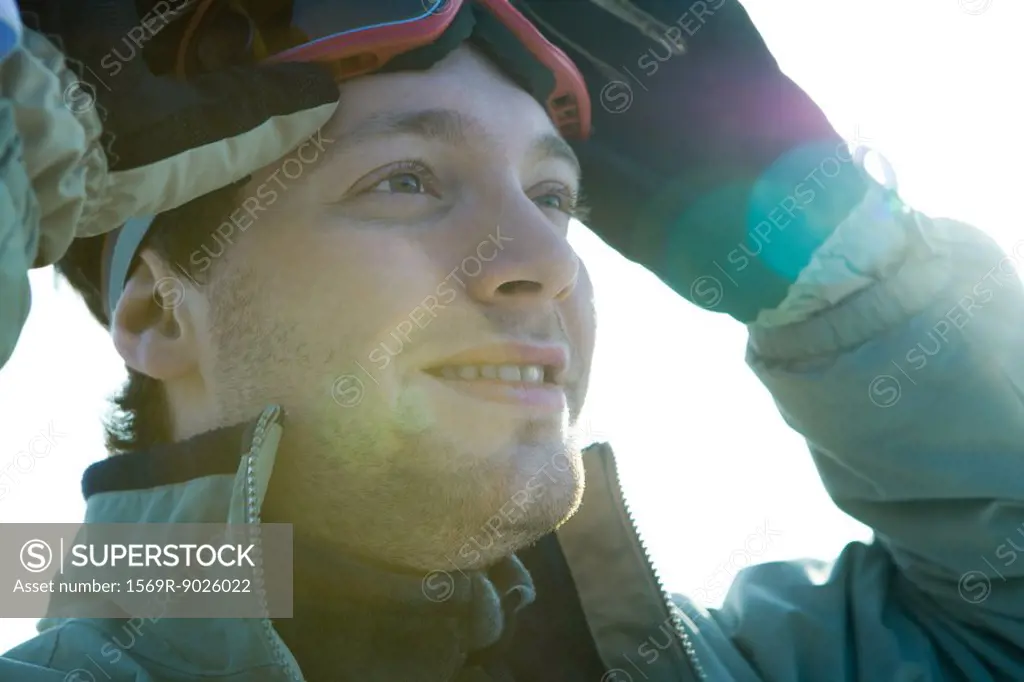 Young man taking off ski goggles, smiling