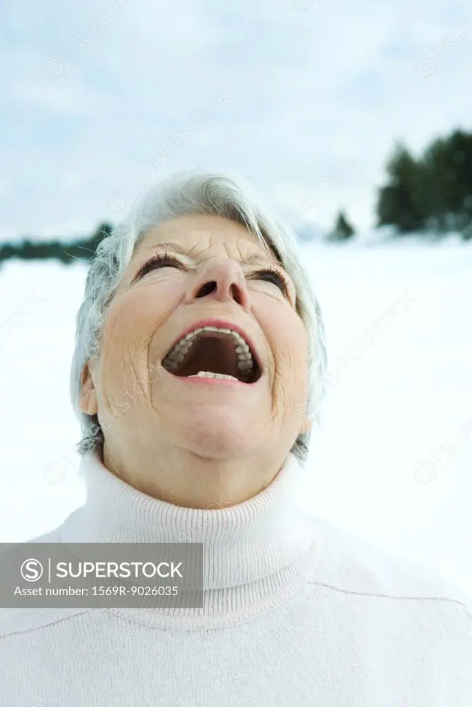 Senior woman laughing in snowy landscape, portrait