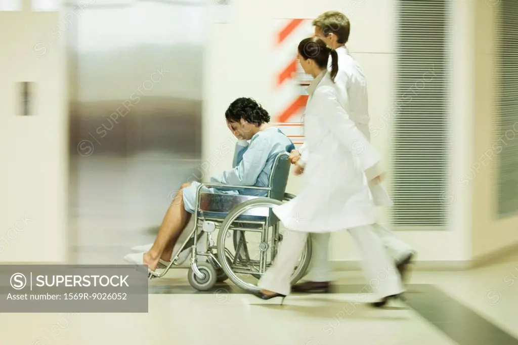 Medical staff pushing man in wheelchair, blurred motion