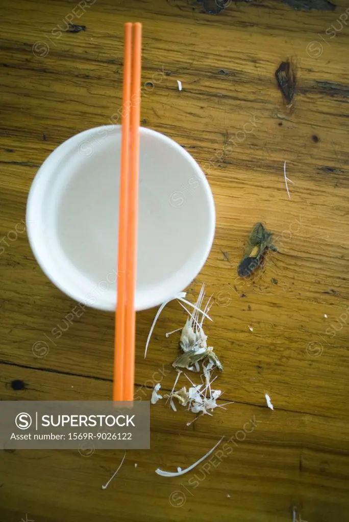 Fish bones on table next to bowl with chopsticks