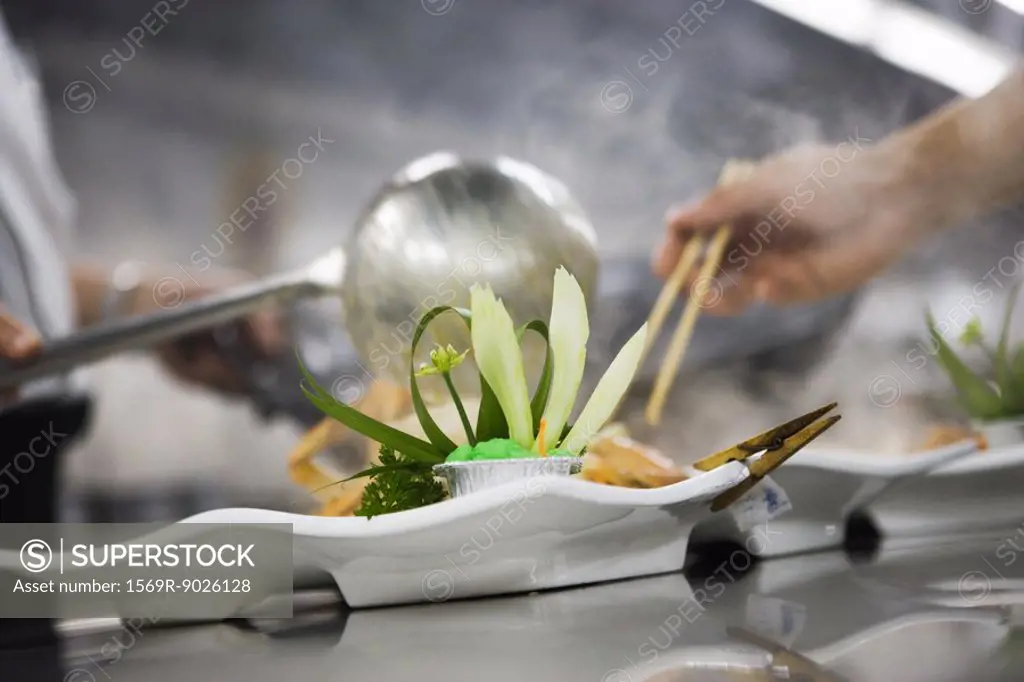 Chefs dressing plates in commercial kitchen