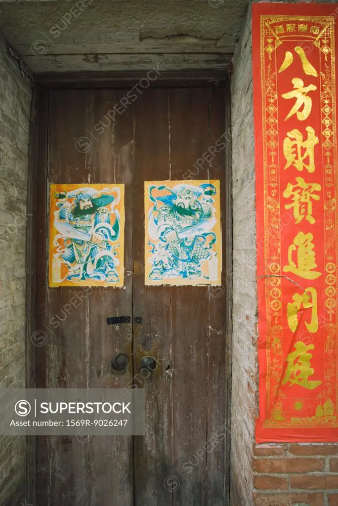 China, doorway with posters, banner with Chinese script next to door