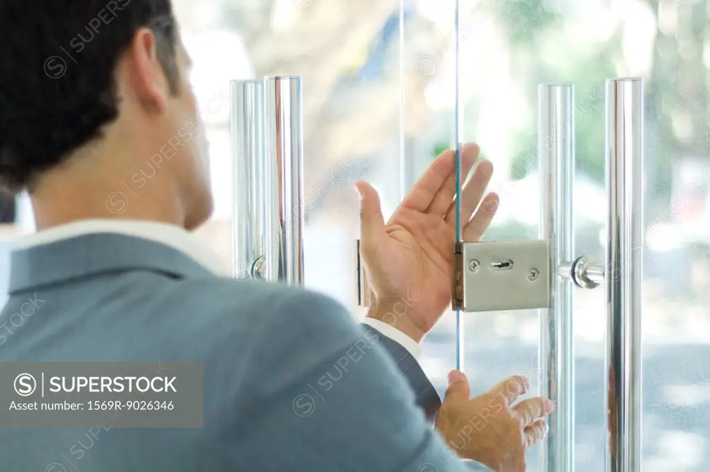 Man inspecting lock on glass door
