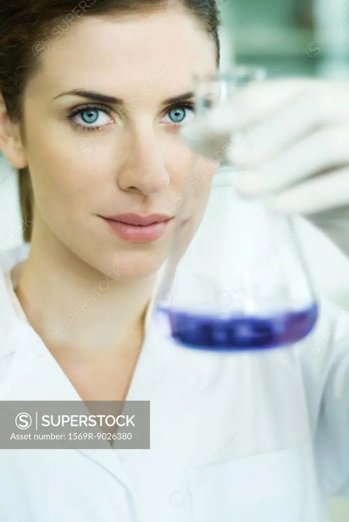 Young researcher holding up conical flask