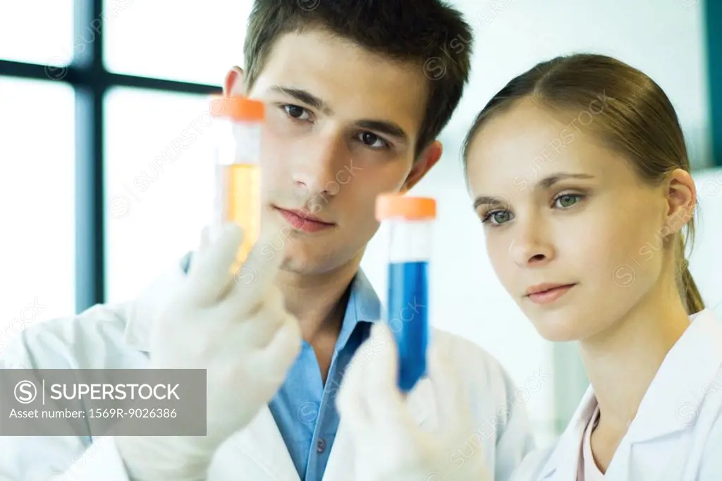 Young male and female lab workers, holding up test tubes
