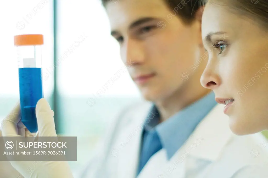 Young male and female lab workers, holding up test tube