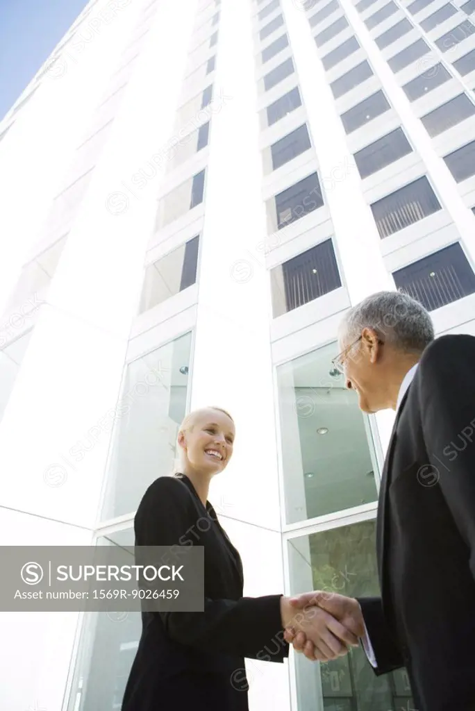 Young businesswoman shaking hands with mature businessman, low angle view