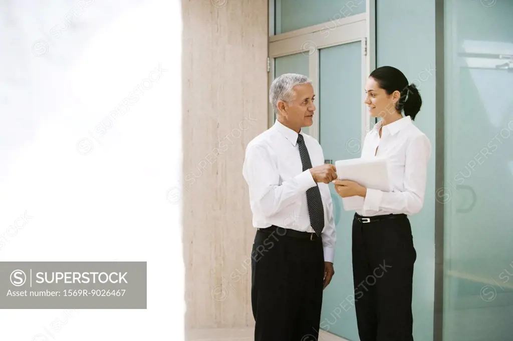 Mature businessman and young businesswoman discussing file