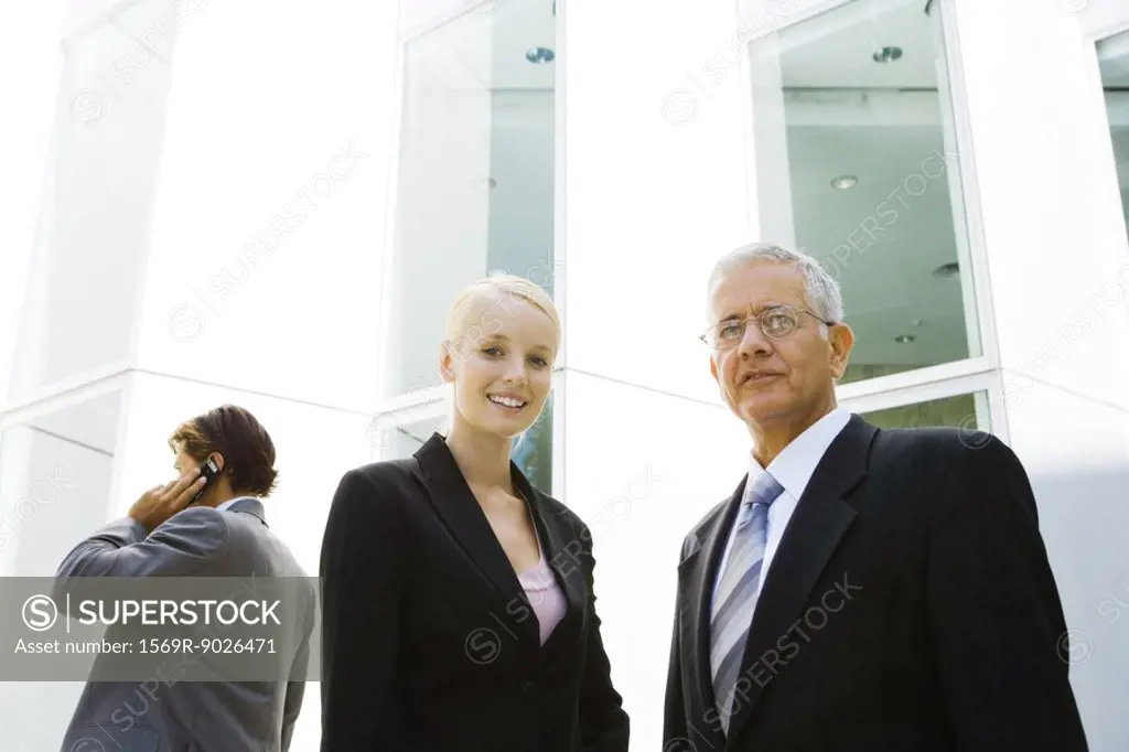 Mature businessman and young businesswoman, low angle view