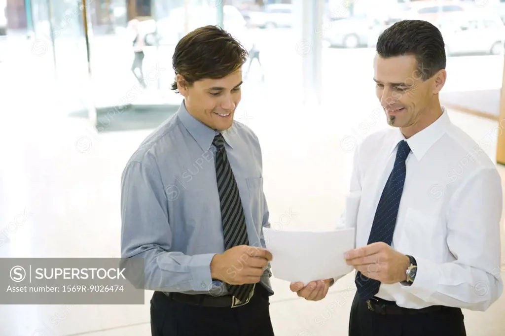Two businessmen looking at document together
