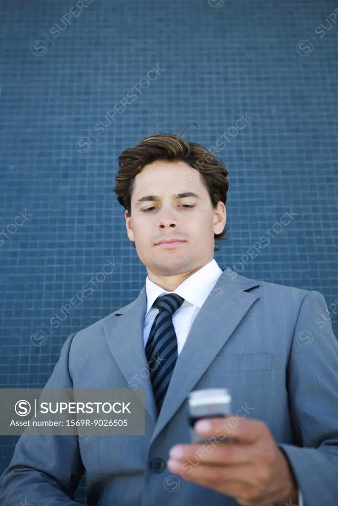 Businessman looking down at cell phone, low angle view
