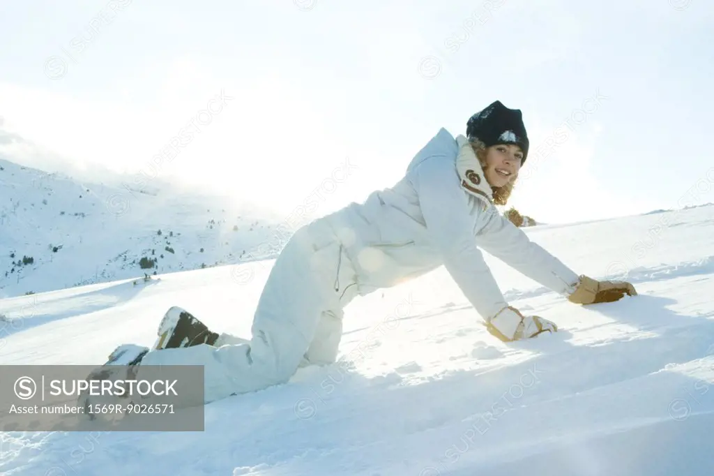 Teenage girl down on all fours in snow, smiling at camera