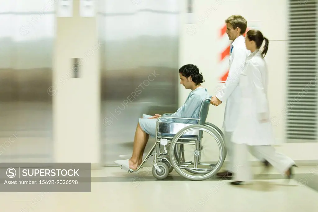 Hospital staff pushing man in wheelchair, blurred motion