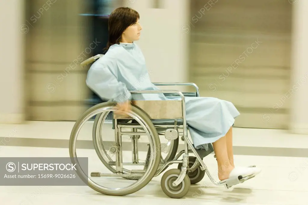 Woman using wheelchair, full length, blurred motion