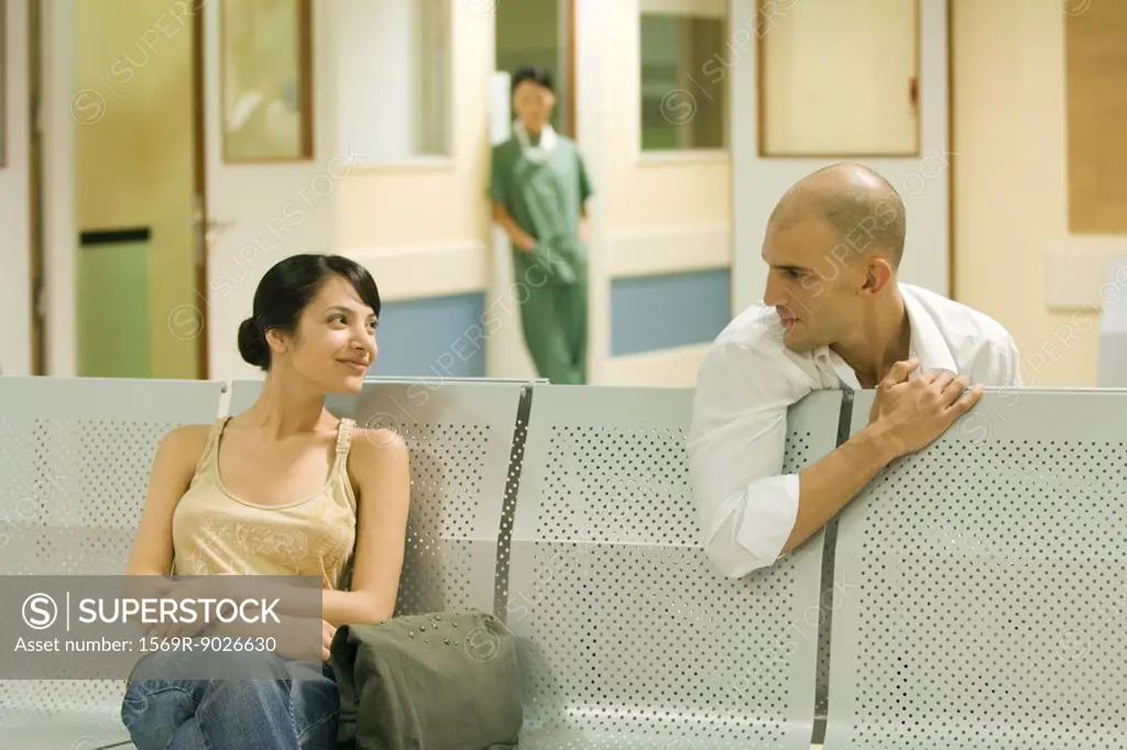 Two adults sitting in hospital waiting room, chatting