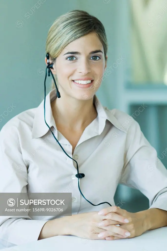 Young businesswoman wearing headset, smiling at camera, waist up