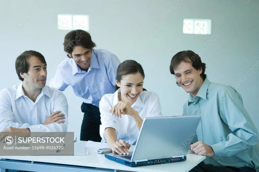 Four business associates using laptop computer, smiling