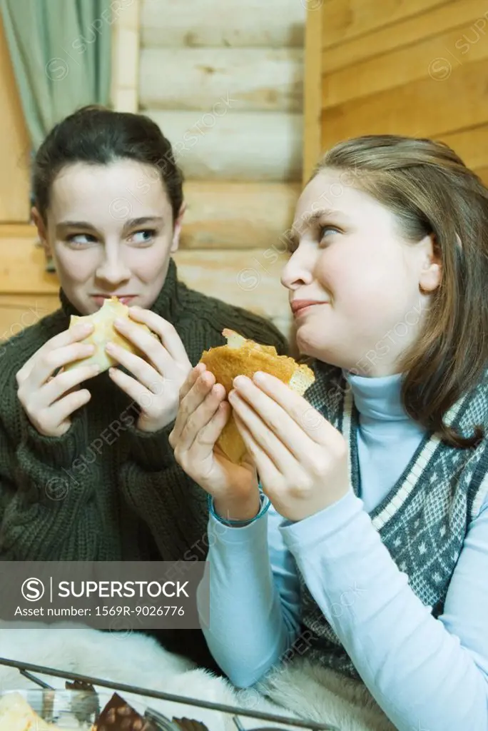 Two teenage girls eating crepes, looking at each other
