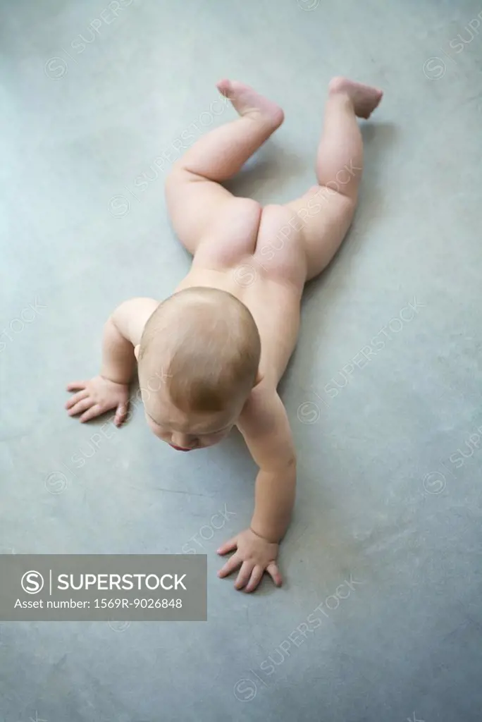 Naked baby crawling on floor, view from directly above, full length