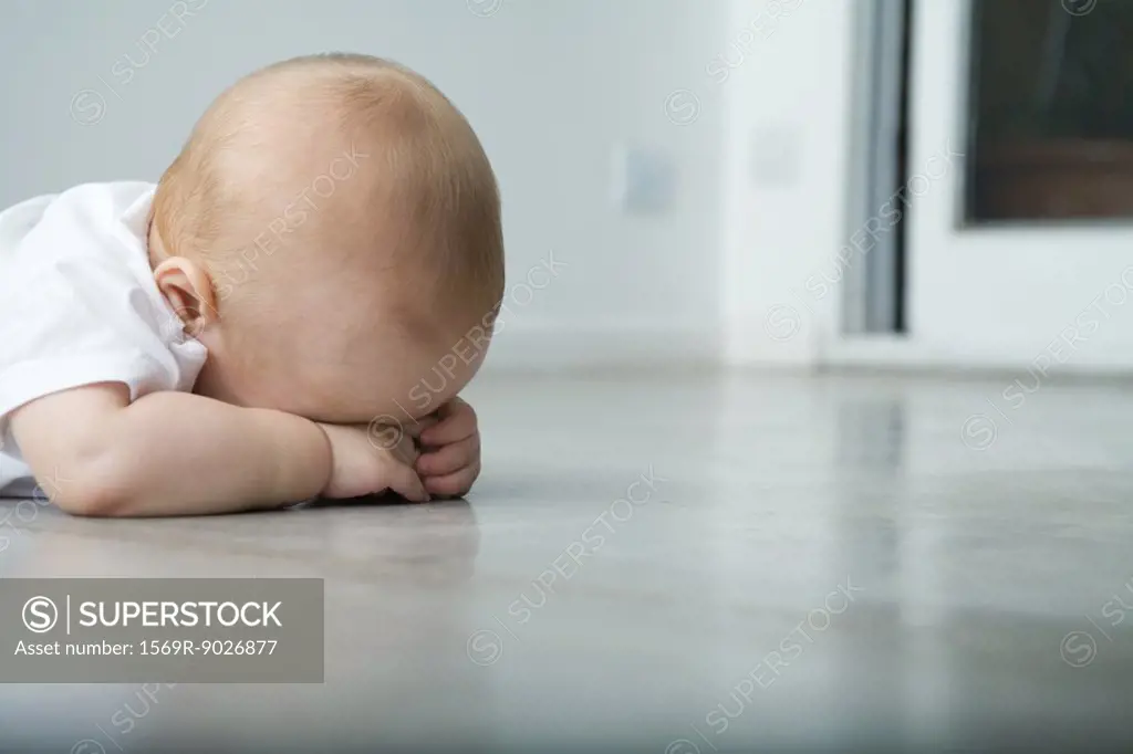 Baby lying on stomach, head resting on arms, obscured face