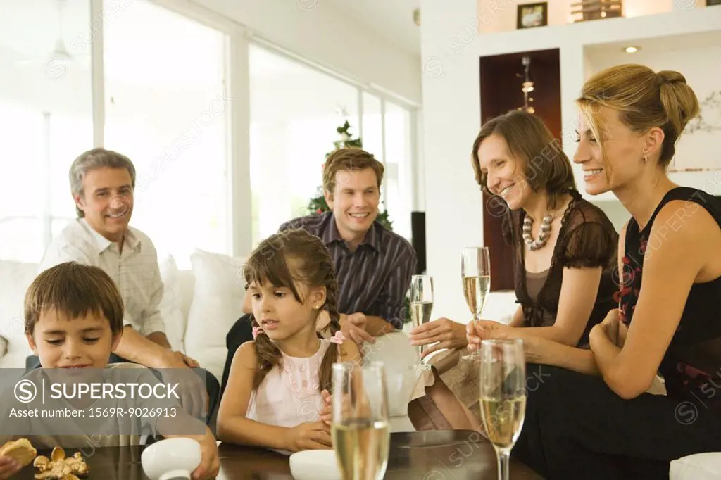 Four adults drinking champagne, watching children, smiling