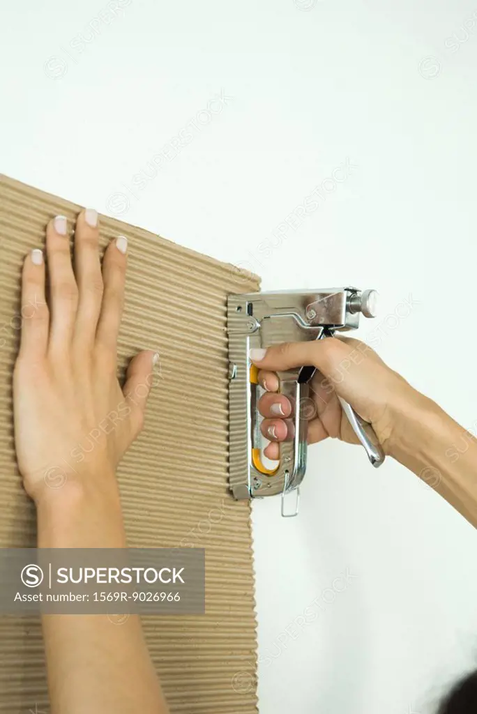 Woman stapling corrugated cardboard, cropped view of hands