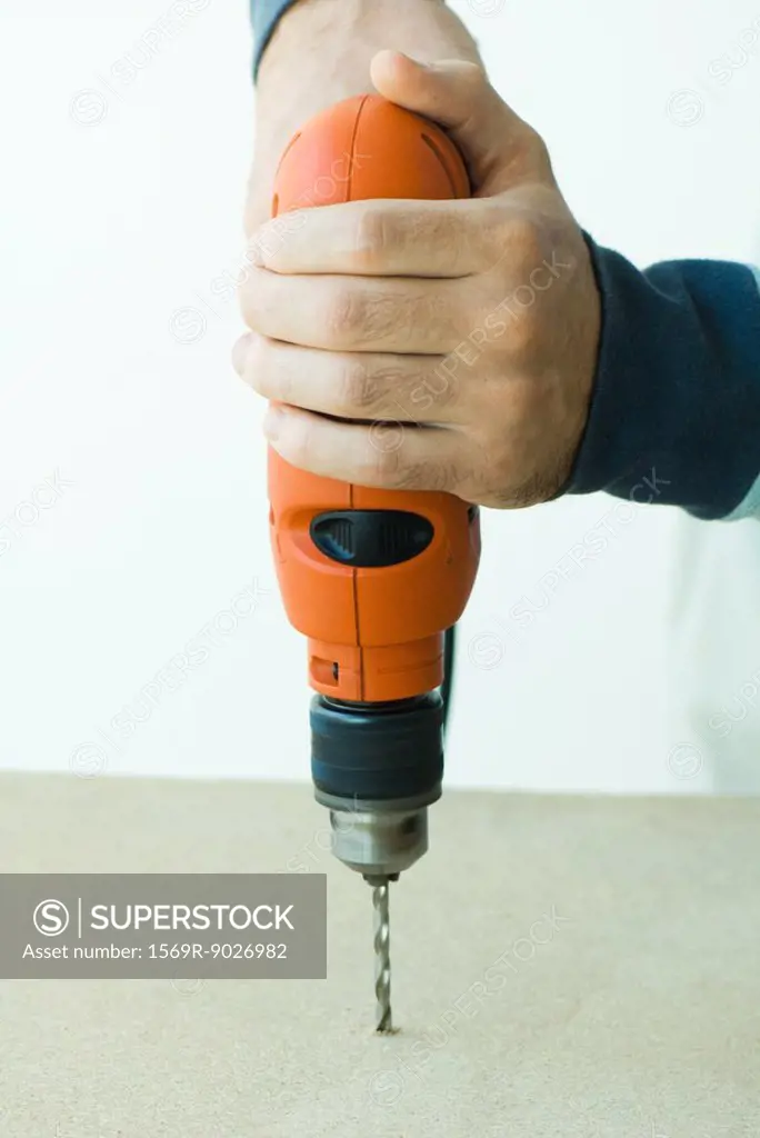 Man using drill, cropped view of hands