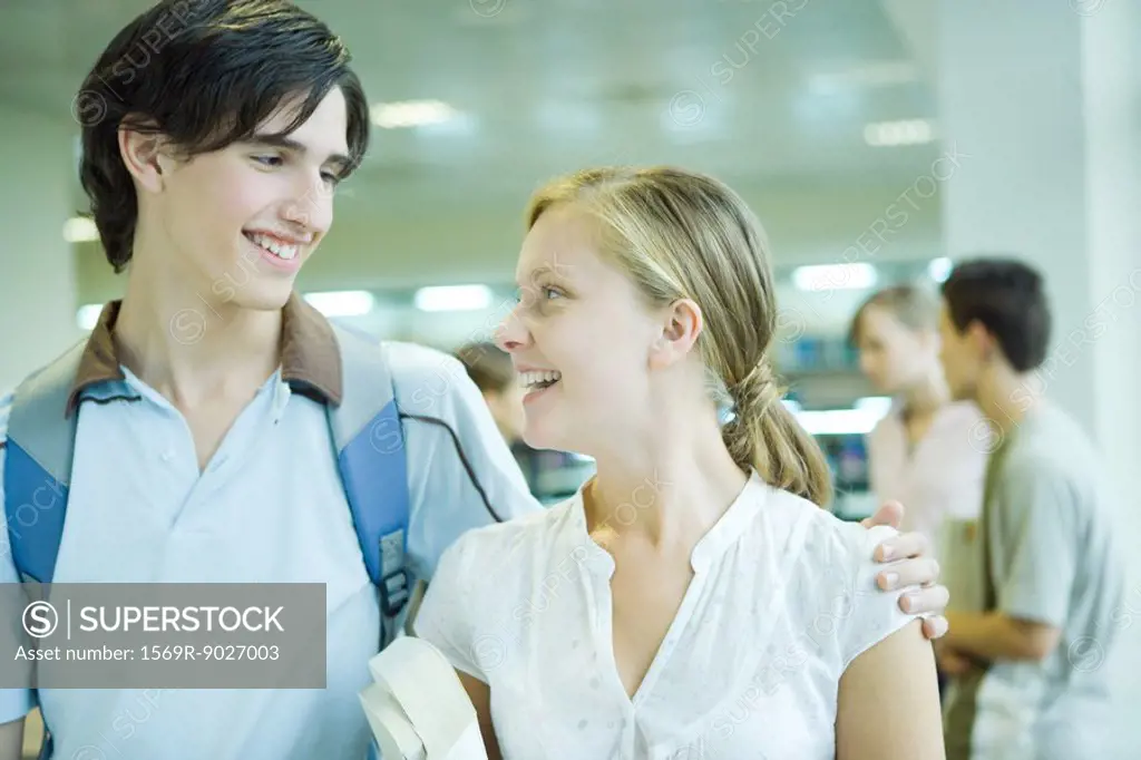 Two students standing together, smiling at each other, one´s arm around the other´s shoulder